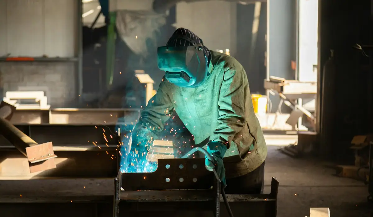 Fabricator welding a steel grill in a workshop